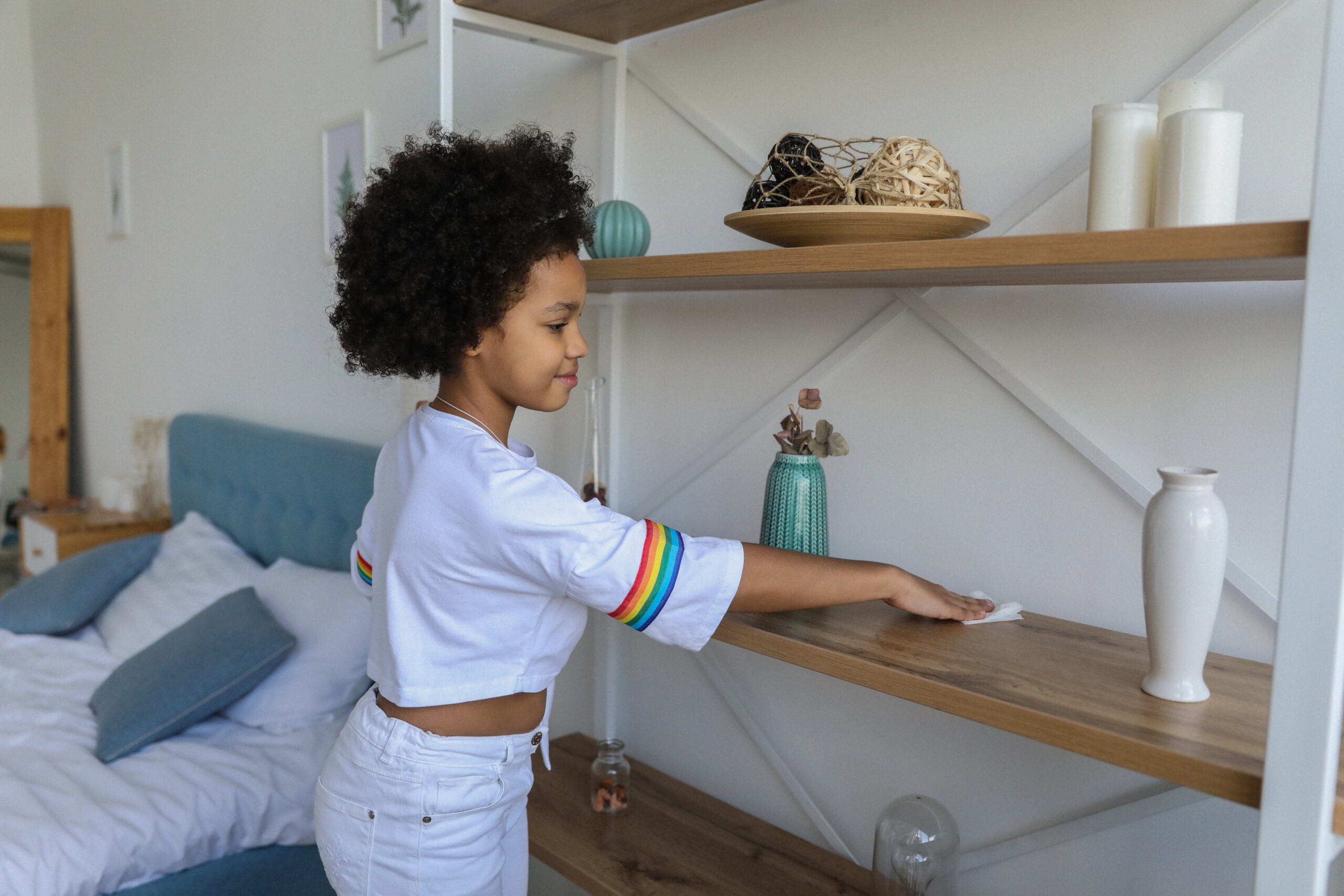 Child dusting a shelf in her room